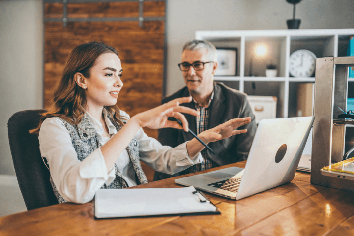 a man and a woman in front of a computer talking&nbsp;